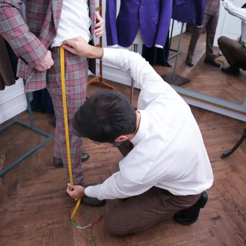 Tailor taking precise leg measurements during a custom suit fitting at Vinny’s Custom Clothes Los Angeles